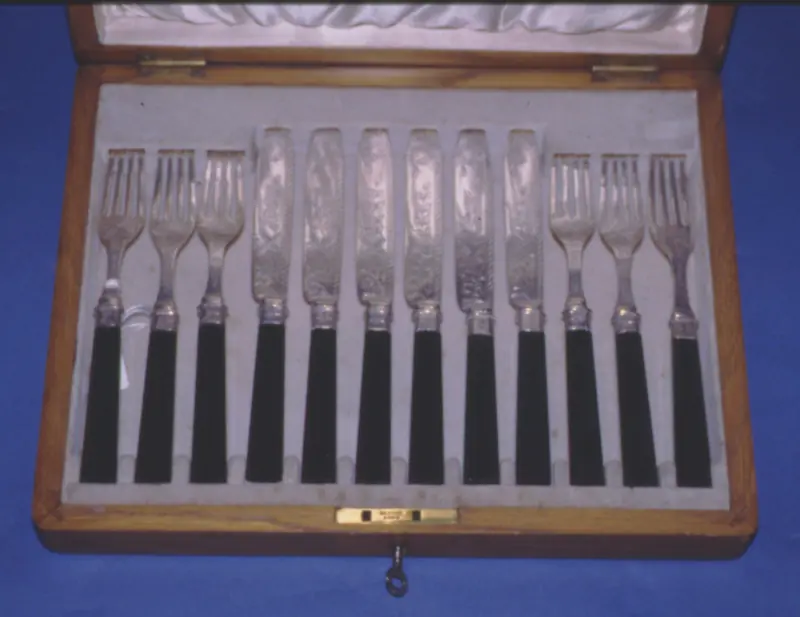 Ménagère de couteaux et fourchettes à dessert en argent dans son coffret en bois